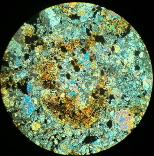 misshapen circular chrondrule with many individual circular grains of different pastel and gray colors